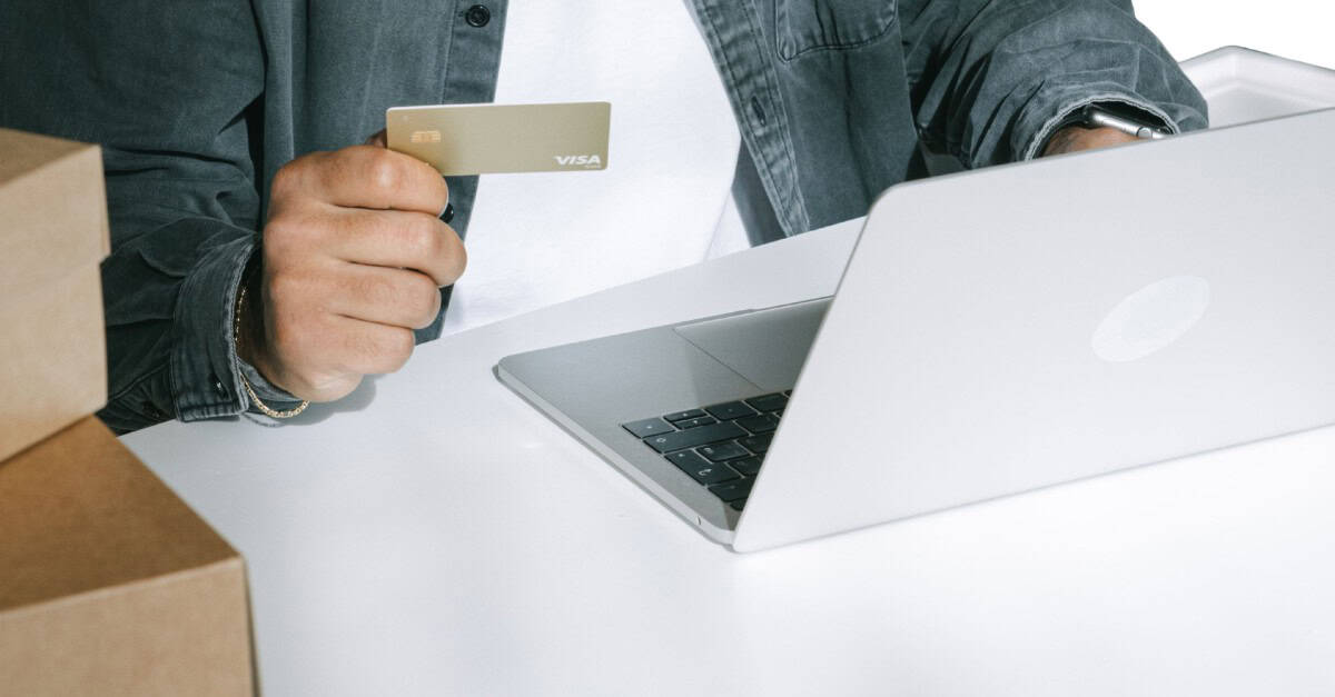Persona comprando en línea con tarjeta y ordenador portátil en oficina moderna.